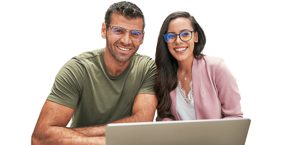 Smiling couple wearing blue-light blocking glasses in front of a laptop on a white background