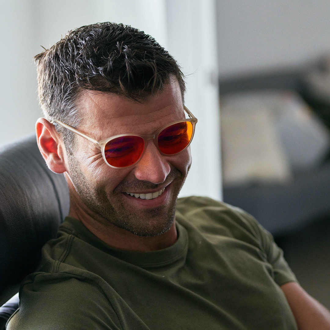 Man wearing blue-light blocking glasses and a green shirt indoors