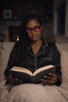 Woman in pajamas reading a book waering Sleep Monroe Swannies