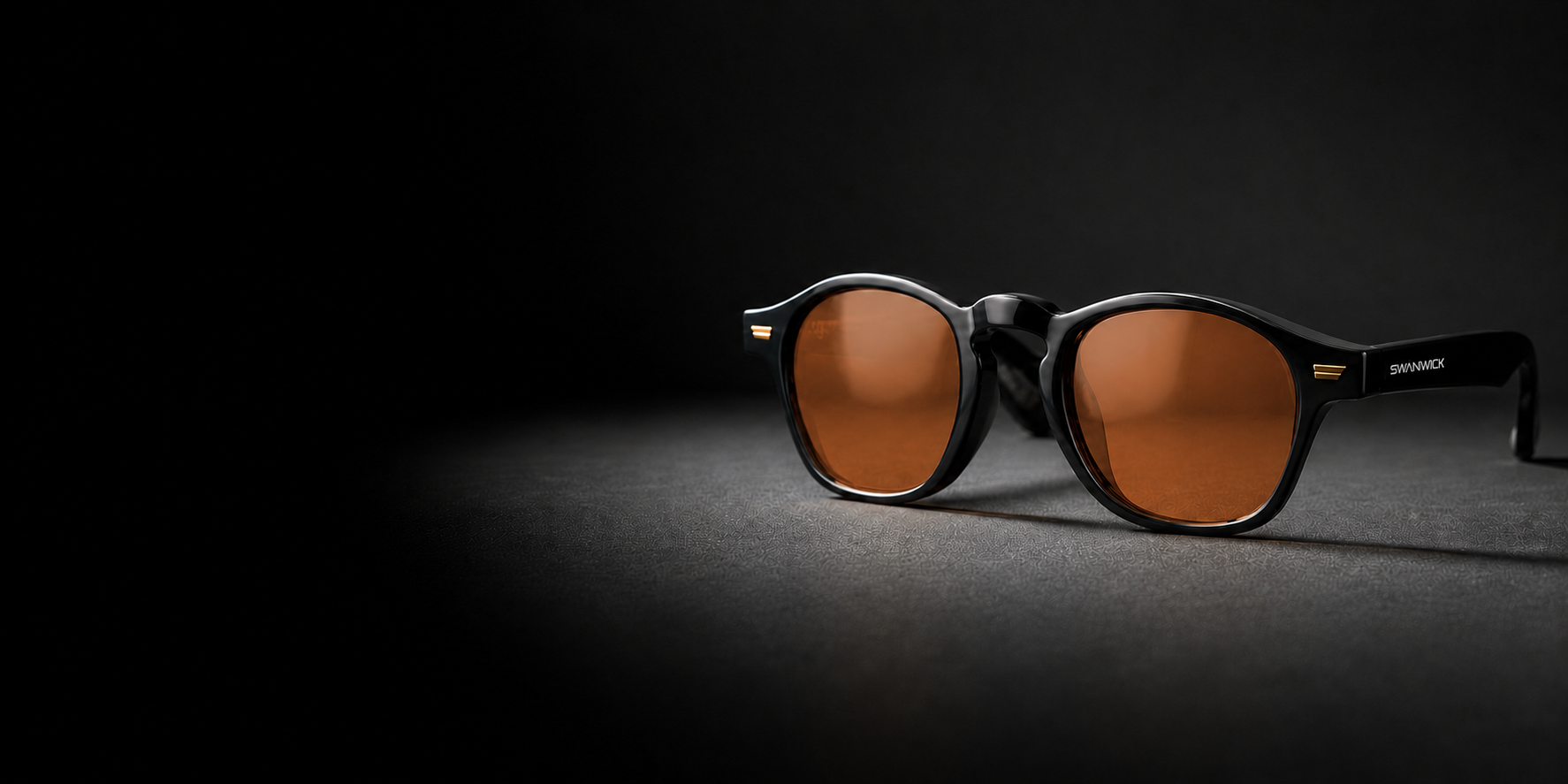 kensington swannies blue light blocking glasses on a black background wtih light shining on them